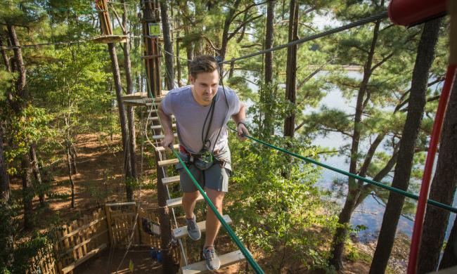 A man crosses a rope bridge at the Go Ape treetop adventure at Memphis' Shelby Farms Park