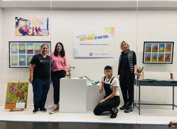 Creative Aging artists posing with their art exhibit at Renasant Convention Center.